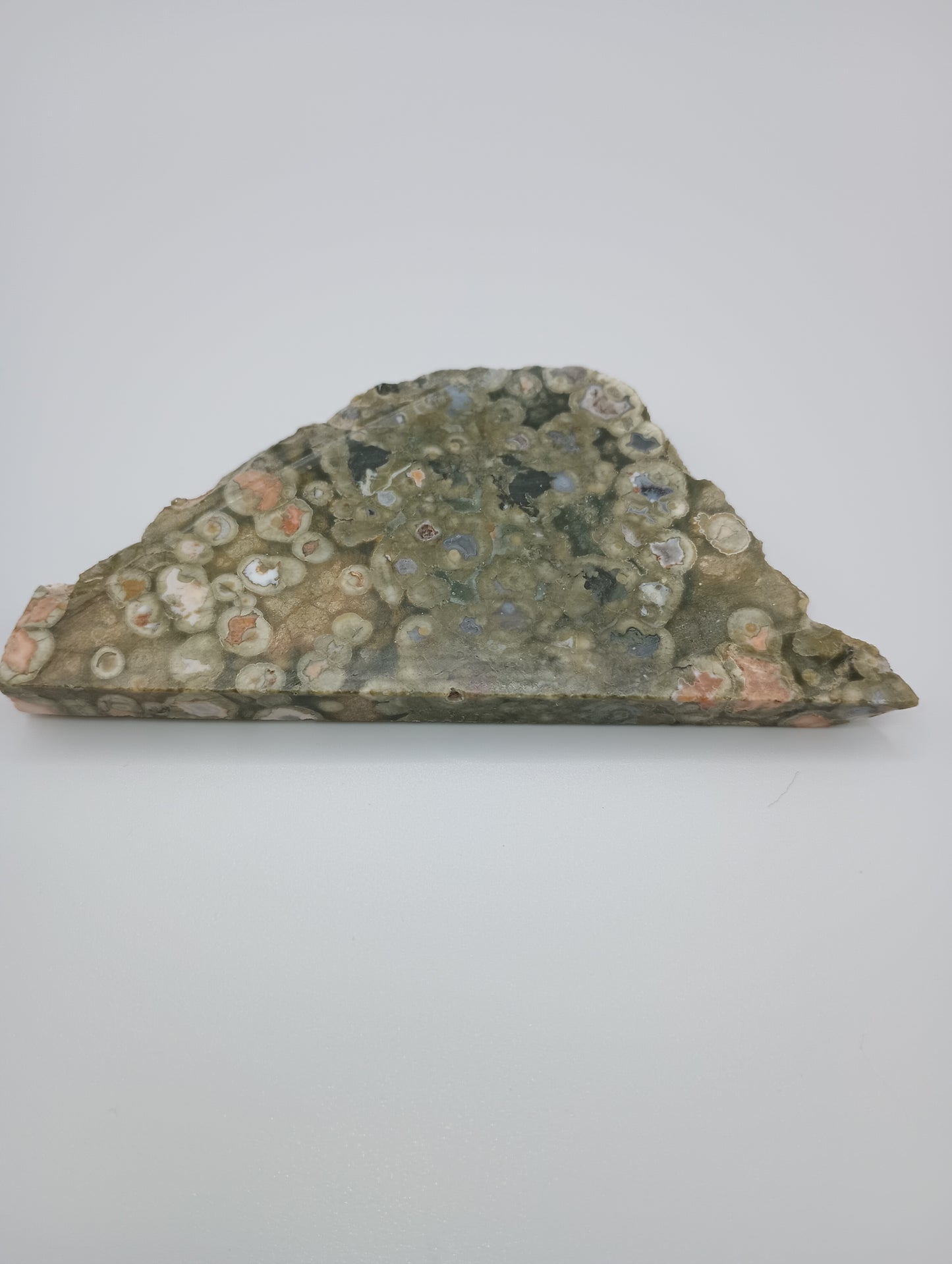 slice of stone with circular pattern of greens, white & peach