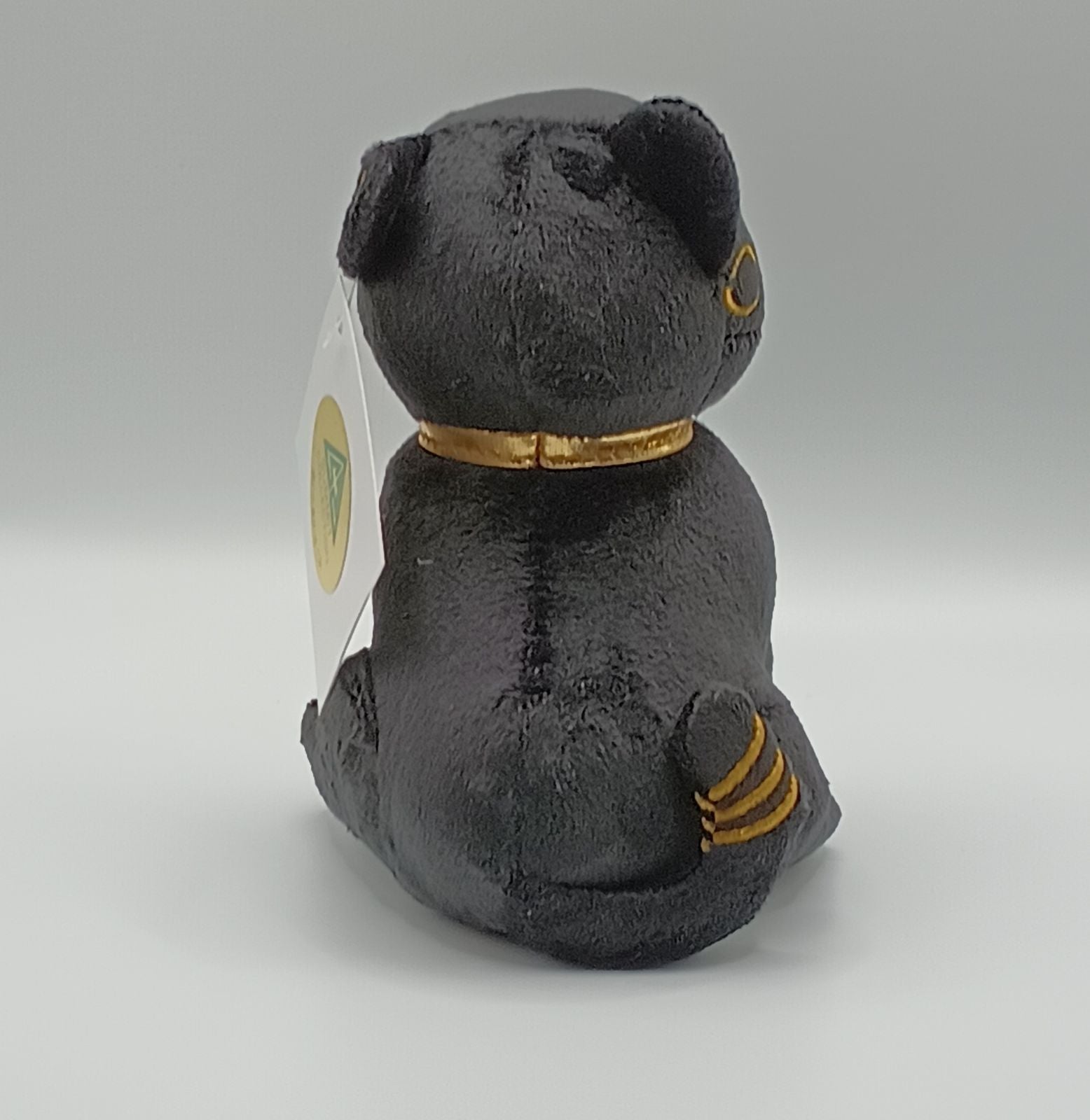 Black bastet plush toy with gold accents on a white background