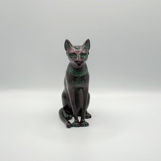 Statue of Bastet, a cat with green eyes and hieroglyphics on a white background