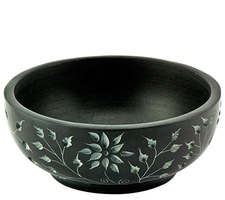 Black stone bowl with floral and leaf carving around outside.